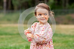 happy baby girl with soap bubble blower in summer