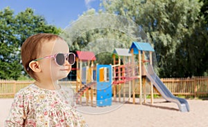 happy baby girl in sunglasses over playground