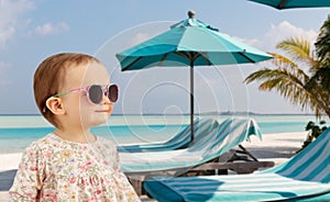 happy baby girl in sunglasses on summer beach