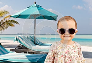 happy baby girl in sunglasses on summer beach