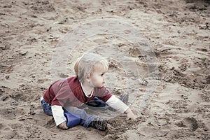 Happy baby girl, toddler, playing with sand on a playground