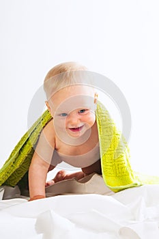Happy baby girl under green towel