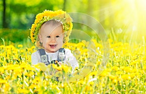 Happy baby girl in a wreath on meadow with yellow