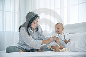 Happy baby girls playing with mother in bedroom. Mother and lovely baby having a good time together