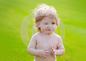 Happy baby in grass on the fieald at sunny summer evening. Smiling child outdoors. Funny little child closeup portrait