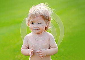 Happy baby in grass on the fieald at sunny summer evening. Smiling child outdoors. Funny little child closeup portrait