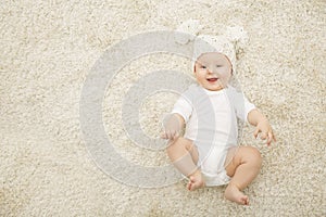 Happy Baby in Hat and Diaper Lying on Carpet Background