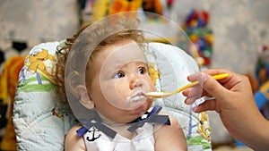 Happy baby in her favorite house. Feeding baby with a spoon.