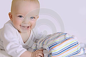 Happy baby holds cloth diaper. Isolated on white.