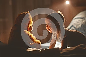 Happy baby laughing with teddy bear in bed