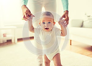 Happy baby learning to walk with mother help