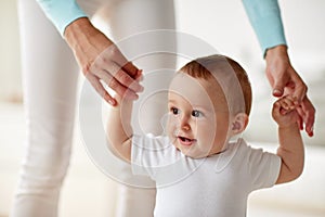 Happy baby learning to walk with mother help