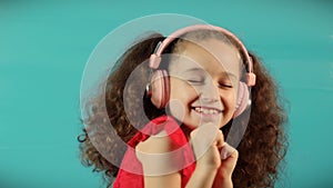Happy baby listening to music on turquoise background at home.Slow motion Dance child relax with closed eyes in