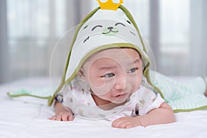 Happy baby lying on bed under blanket