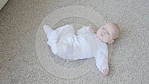 Happy Baby Lying on Carpet Background, Smiling Infant Kid girl in White Clothing