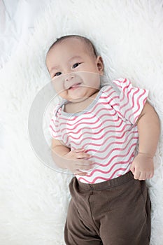 Happy baby lying on white bed
