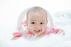 Happy baby lying on white bed