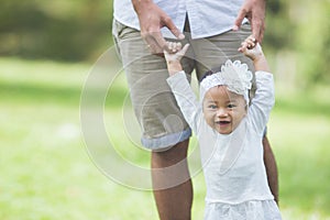 Happy baby making her first steps on a green grass