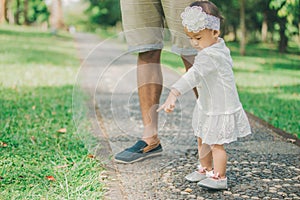 Happy baby making her first steps on a green grass