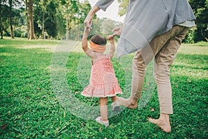 Happy baby making his first steps on a green grass