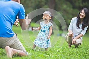 Happy baby making his first steps on a green grass