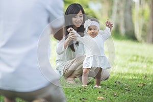 Happy baby making his first steps on a green grass