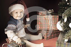 Happy baby with many gift box near decorated Christmas tree