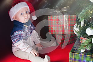 Happy baby with many gift box near decorated Christmas tree