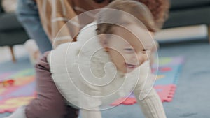 Happy, baby and mother playing while crawling on the floor in the living room with a smile, laughing and happiness