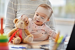 Happy baby with mother working at home office