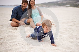Happy, baby and parents on beach in sand, summer and family fun with child crawling. Laughing, smile and couple with kid