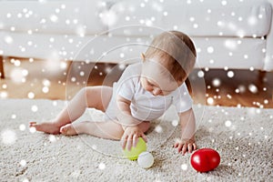 Happy baby playing with balls on floor at home