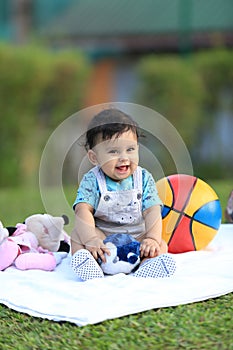 Happy baby playing outdoors with colourful ball