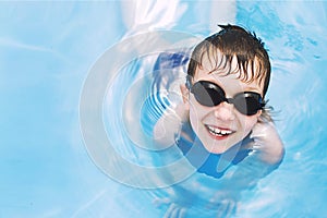 Happy baby in the pool. boy swims in the pool with swimming glasses. .