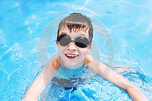 Happy baby in the pool. boy swims in the pool with swimming glasses.