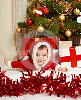 Happy baby portrait in christmas decoration, lie on fur near fir tree and gifts, winter holiday concept