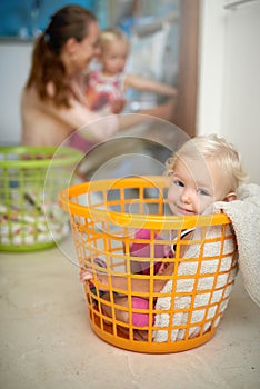 Happy baby, portrait and laundry basket with mom for fun childhood, game or chore day at home. Young, little girl and
