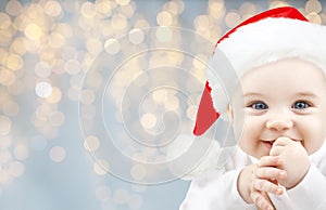 Happy baby in santa hat over holidays lights