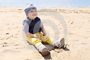 Happy baby sitting on shore of the lake