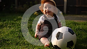 Happy Baby Sitting With Soccer Black White Classic Ball On Green Grass. Adorable Infant Baby Playing Outdoors In