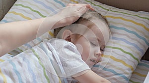 Happy baby sleeping in a crib mom covers baby with a blanket. Mom put her tired daughter to bed. Cute baby is resting in