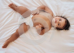 Happy baby, smile and relax on bed in family home bedroom for diaper change, bedtime or healthy childcare. Child