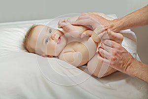 Happy baby smiling and playing with feet on white background