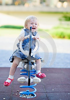 Happy baby swinging on horse on playground
