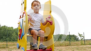 Happy baby swinging on a swing in the playground.