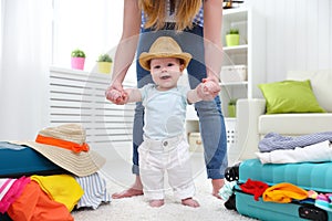 Happy baby taddler makes the first step with mother and bags to