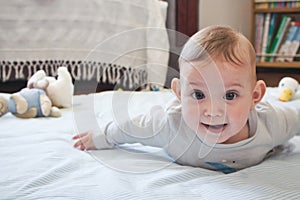 A happy baby toddler child lying on a play mat looking directly at the camera and smiling - tummy time concept