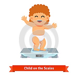 Happy baby toddler in diaper weighting on a scales photo