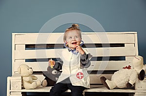 Happy baby with toy pets sit on wooden bench