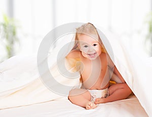 Happy baby under a blanket laughing